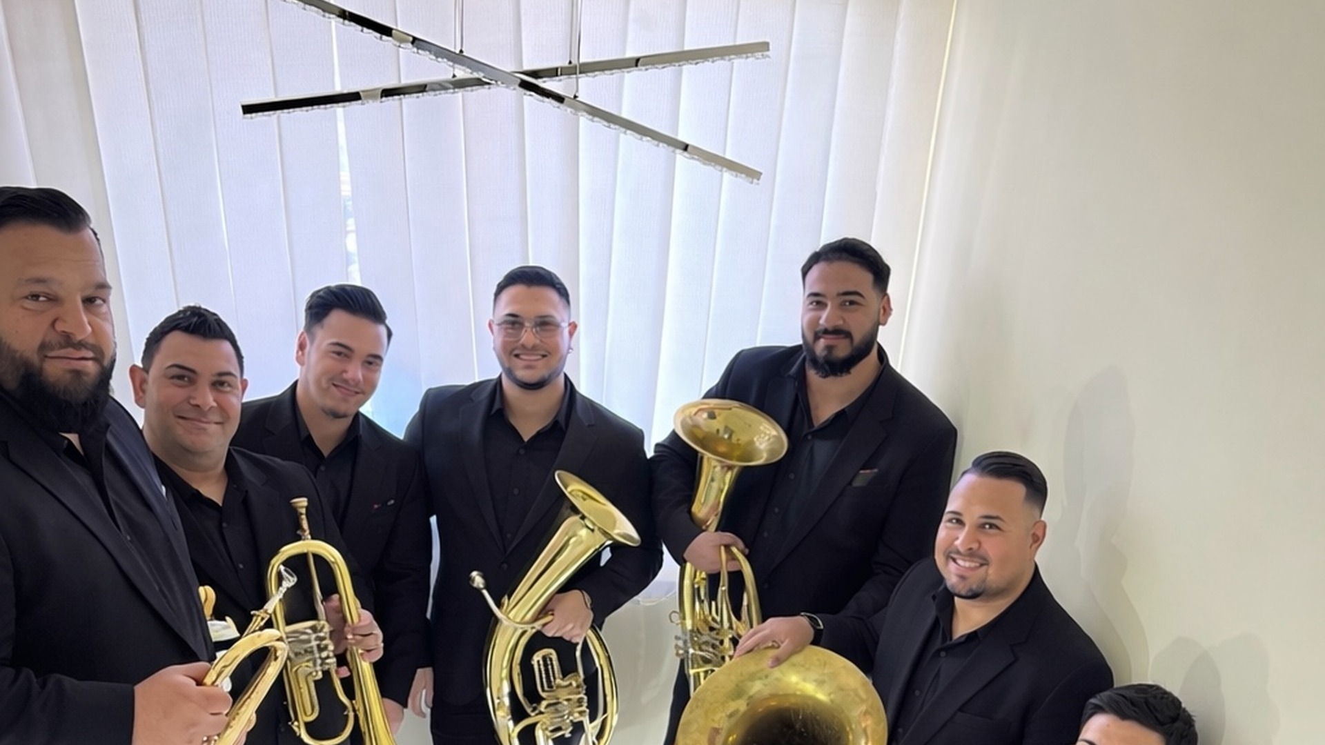 Šest muzičara orkestra u crnim odelima sa trubama i tenor hornom pred nastup u sali