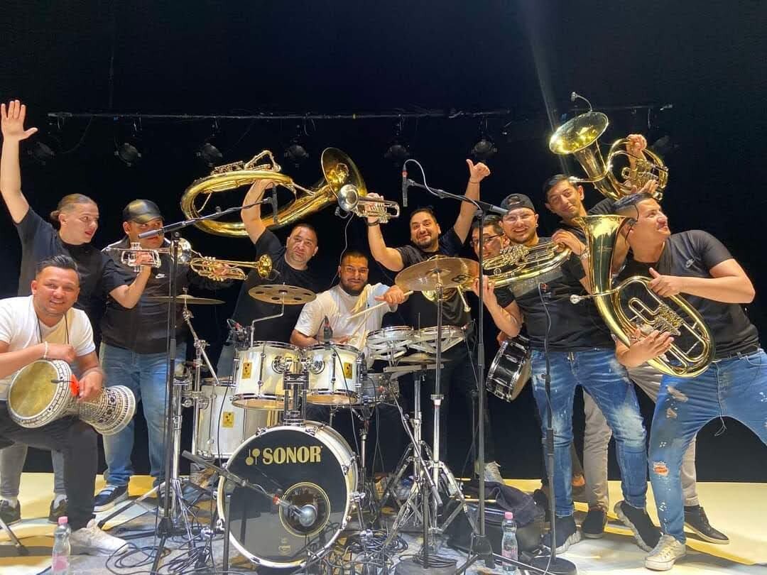 Muzičari oko bubnjeva, sa trubama i tapanom podignutim uvis